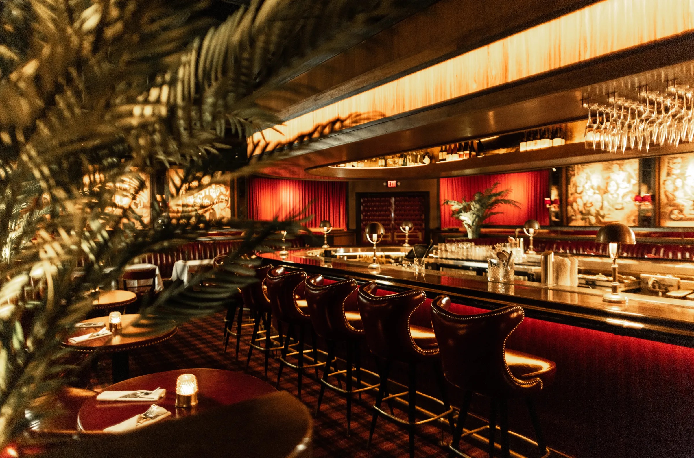 Warm restaurant lounge with red banquettes, built-in wood details, and brass lighting