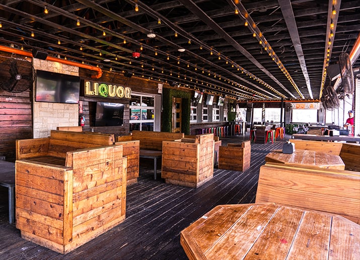 Prospect Park covered patio with wood booths, wood tables, deck flooring, and colorful stools
