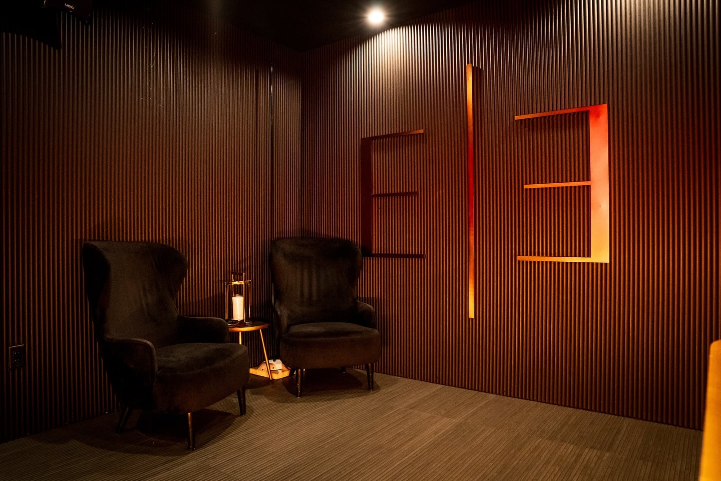 Thirteen lounge chairs with a small table and ribbed wood millwork wall