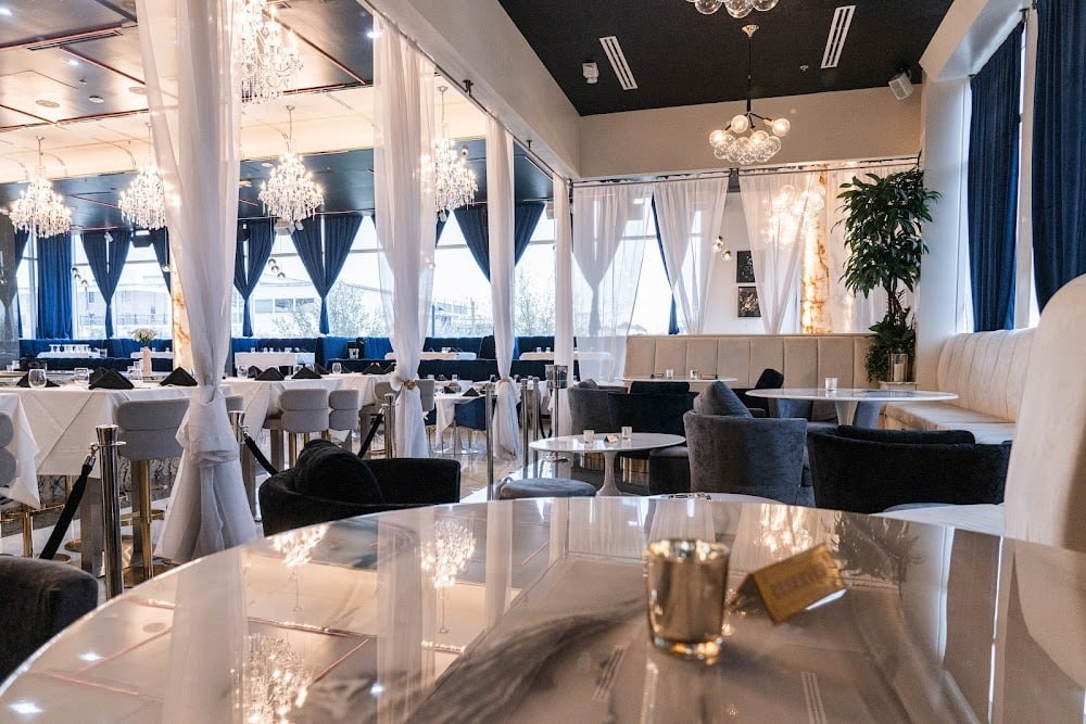 White upholstered banquette seating with dining tables, chairs, and warm restaurant lighting